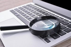 a magnifying glass on a laptop symbolising finding an acoountant